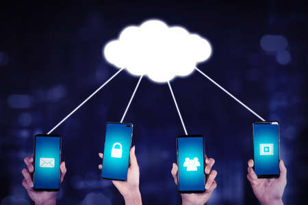 Close up of four hands showing smartphones connected by cloud computing storage and access file, image, video, and emailの写真素材