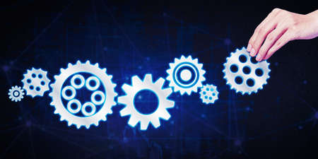 Close up of businessman hand arranging cogwheels on the virtual screen while working