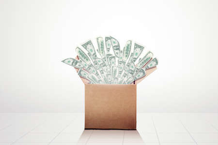 Image of money bulging out of a cardboard box in the studio. Isolated on white backgroundの写真素材