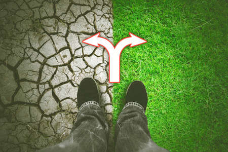 Close up of young man foots standing between green and dried groundの写真素材