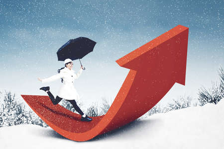 Happy woman holding umbrella while running above upward arrow under snowfall at winter time