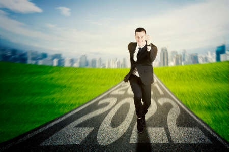 Caucasian businessman running on the road with 2022 numbers while smiling at the cameraの写真素材