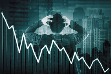 Double exposure of stressed businessman scratching his head while standing with declining arrow in modern city backgroundの写真素材