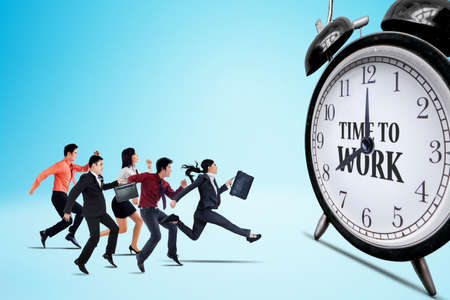 Group of business people running fast toward alarm clock with text of time to work in the studio...