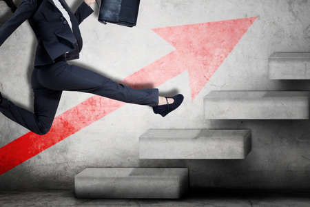 Close up of businesswoman feet running on the stairs with red upward arrow on the wallの写真素材