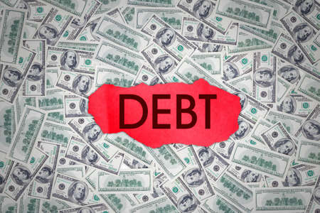 Top down view of red paper with debt word above piles of banknotes dollarの写真素材