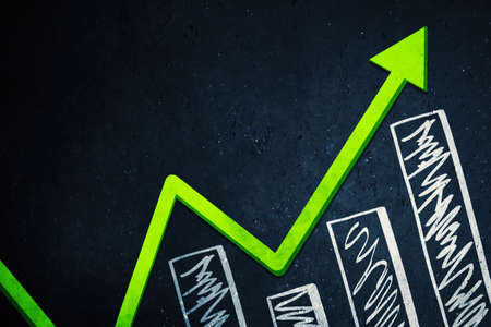 Close up of green upward arrow and growth graph on the chalkboard backgroundの写真素材