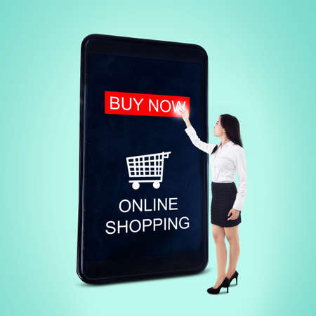 Young woman touching buy now button on the cellphone apps while doing shopping onlineの写真素材