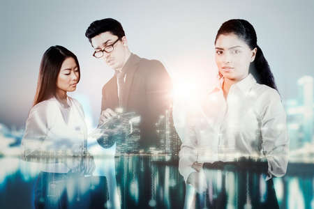 Double exposure of confident businesswoman standing with her employees in modern city background