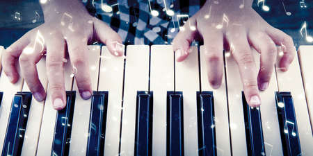 Close up of little girl hands pressing the keys of a piano with music notes symbol at the home