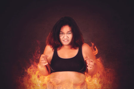 Fat young woman feeling passionate to get weight loss while standing with fireの写真素材