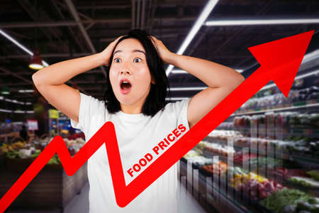Shocked woman looking at increasing food prices while standing in the supermarketの写真素材