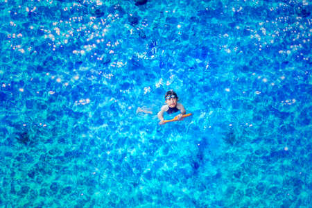Top down view of happy little boy wearing glasses while swimming on the poolの写真素材