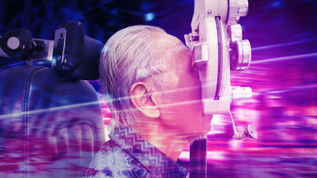 Side view of old man doing eyesight measurement with optical phoropter while sitting with blurred...
