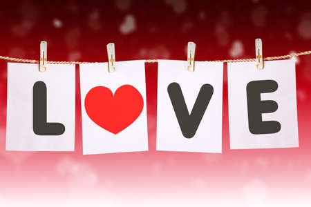 Close up of love word with heart symbol on white papers hanging on the rope in blurred sparkling lights backgroundの写真素材