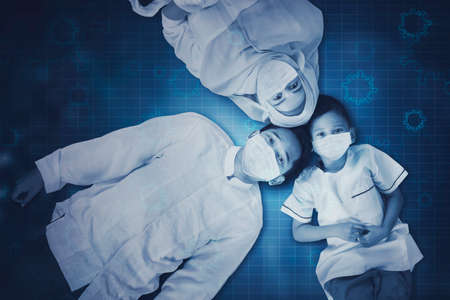 Top view of Muslim young family wearing face mask while lying together with virtual screen backgroundの写真素材