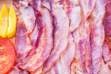 Close up of baked pork meat slices on the wooden plate above the tableの写真素材