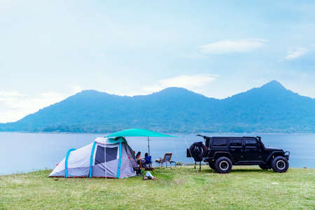 Young family having camp on the Jatiluhur reservoir while enjoying holiday and sitting near the car