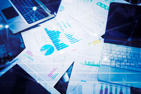 Top down view of digital device with business report documents with connection network lines on virtual screen backgroundの写真素材