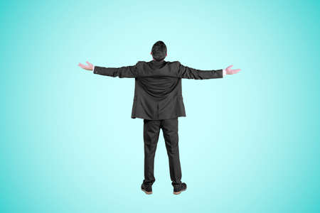 Rear view of male manager expressing success by raising hands while standing in the studio with tosca backgroundの写真素材