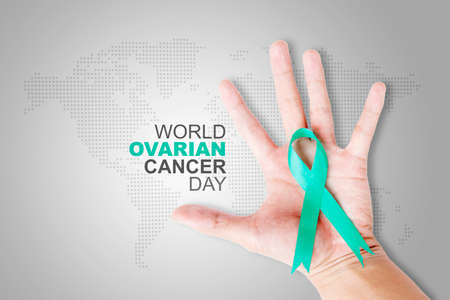 Close up of young woman hand showing teal ribbon with world ovarian cancer day text in the studio. Isolated on white backgroundの写真素材