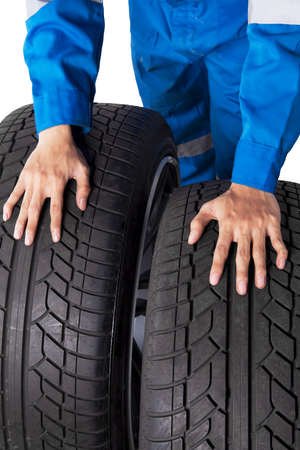 Close up of mechanic hands pushing two tires in the studio. Isolated on white background
