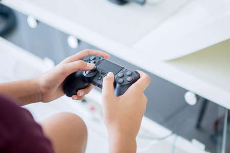 Close up of preteen boy hands using a joystick while playing video games at homeの写真素材