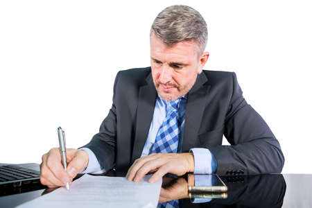 Close up of male manager signing a document while working with a laptop computer in the studio....