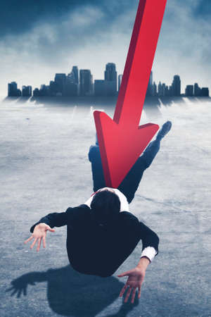 Businessman attacked by declining arrow while lying on the road with silhouette of city background