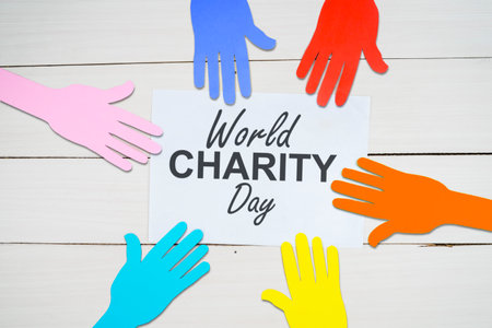 Top down view of world charity day text on the paper with colorful paper hands above the white tableの写真素材