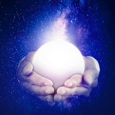 Close up of unknown hands holding a bright moon in the night sky with milky way backgroundの写真素材