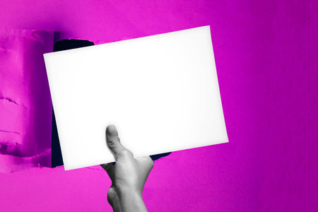 Blank empty paper in man hand covering up a hole in the backgroundの写真素材