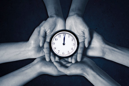 Three people holding an alarm clock together in black and white photographの写真素材