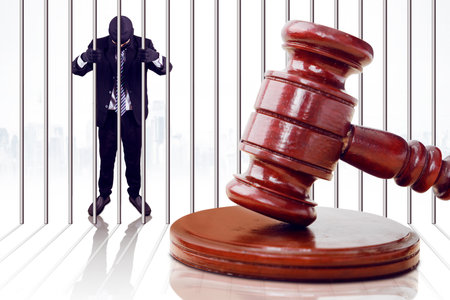 Businessman Hand Holding Metal Bars In Jail with gavel closeup photo shot at front