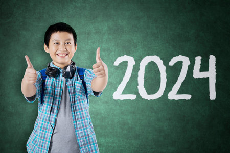 Asian male teenagers showing thumbs up next to 2024 new year numbersの写真素材