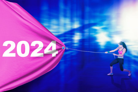Picture of healthy indian woman wearing sportswear and pulling a big flag with the 2024 new year numbersの写真素材