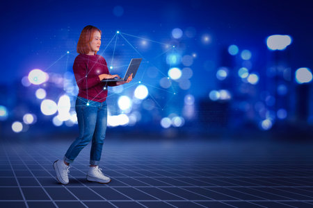 Young woman using laptop while standing over futuristic technology background - metaverse - cyberspaceの写真素材