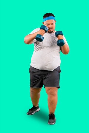 Overweight Asian man training with dumbbells over green backgroundの写真素材