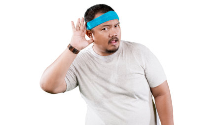 Asian overweight man with hand over ear listening an hearing to tips, rumor or gossipの写真素材