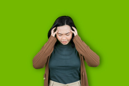 Young beautiful Asian woman wearing winter sweater with hands on head suffering from headache desperate and stressed because pain and migraineの写真素材