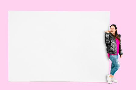Profile side view portrait of attractive cheerful Asian girl wearing jacket demonstrating copy space isolated over white backgroundの写真素材