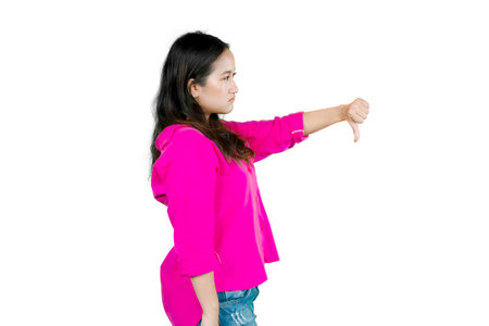 Young asian woman standing looking unhappy and angry showing rejection and negative with thumbs down...