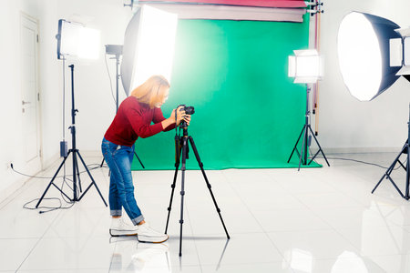 Young Asian female assistant photographer setting the camera and tripod in a photography studioの写真素材