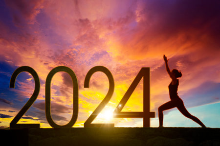 Silhouette of a woman exercising yoga with 2024 new year numbers on the hill at sunrise timeの写真素材