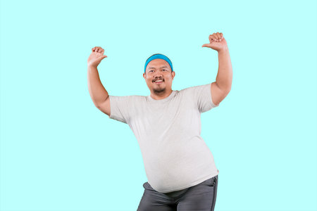funny fat Asian man in white t-shirt smiling and dancing happily, joyful expressing celebrating good newsの写真素材