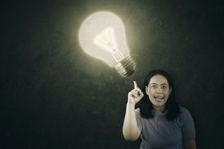 Overweight Asian woman with AHA moment. Bright light bulb in the backgroundの写真素材