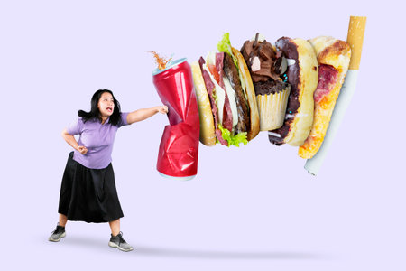 Picture of beautiful fat woman punching soft drink and fast food, isolated on grey backgroundの写真素材