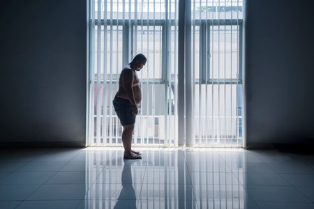 Asian 30s overweight man weighing himself with a scale in front of a windowの写真素材
