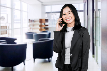 Smiling Businesswoman Talking on Mobile Phone in Modern Office â€“ Professional Communication...