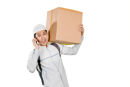 Happy Man Holding a Cardboard Box While Talking on Smartphone, Isolated on Whiteの写真素材